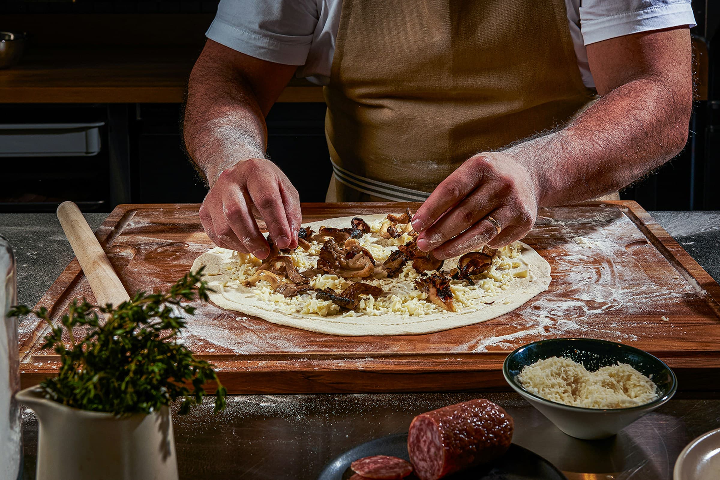 A cook stretching pizza dough on a floured board